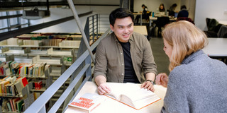 Studierende in der Bibliothek Zwei Studierende sitzen an einem Arbeitsplatz in der Bibliothek und lesen.